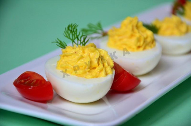 Appetizer eggs stuffed with greens with hard cheese