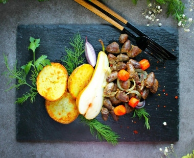 Fried chicken hearts with onions in a pan