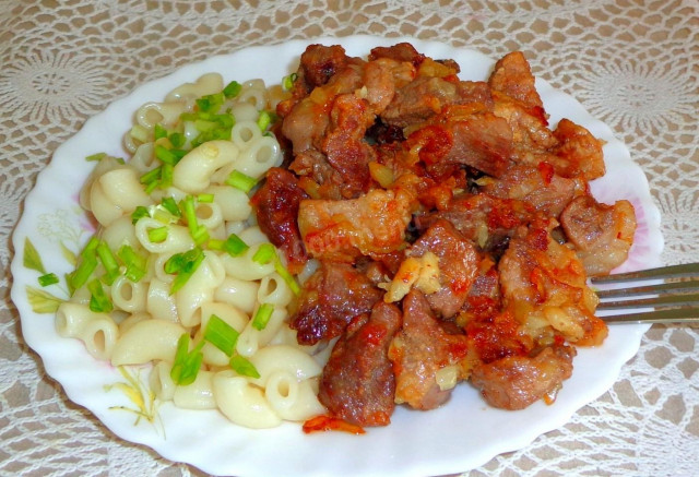 Fried pork pieces in a frying pan with onions