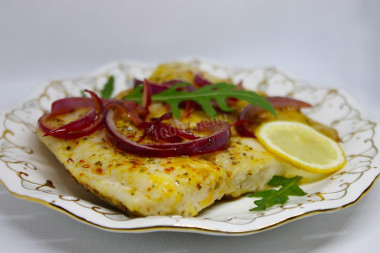 Pangasius in a frying pan with fried onion