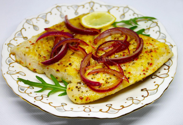 Pangasius in a frying pan with fried onion