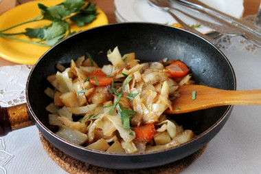 Cabbage and potatoes, fried onions and carrots in a frying pan