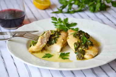 Fried chicken fillet in a pan with lemon and herbs