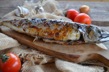 Grilled mackerel on a grill on coals in foil baked