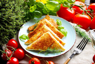 Triangles of pita bread with ham and cheese in a frying pan