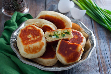 Pies with egg and green onions in a frying pan