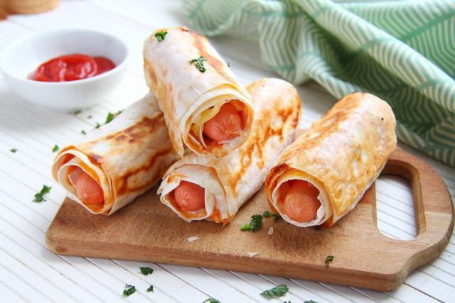 Sausages in pita bread in a frying pan with cheese