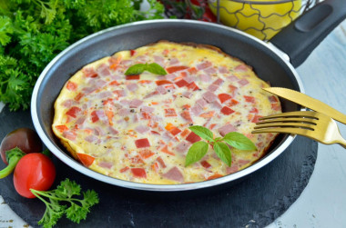 Fluffy omelet with milk and sausage in a frying pan